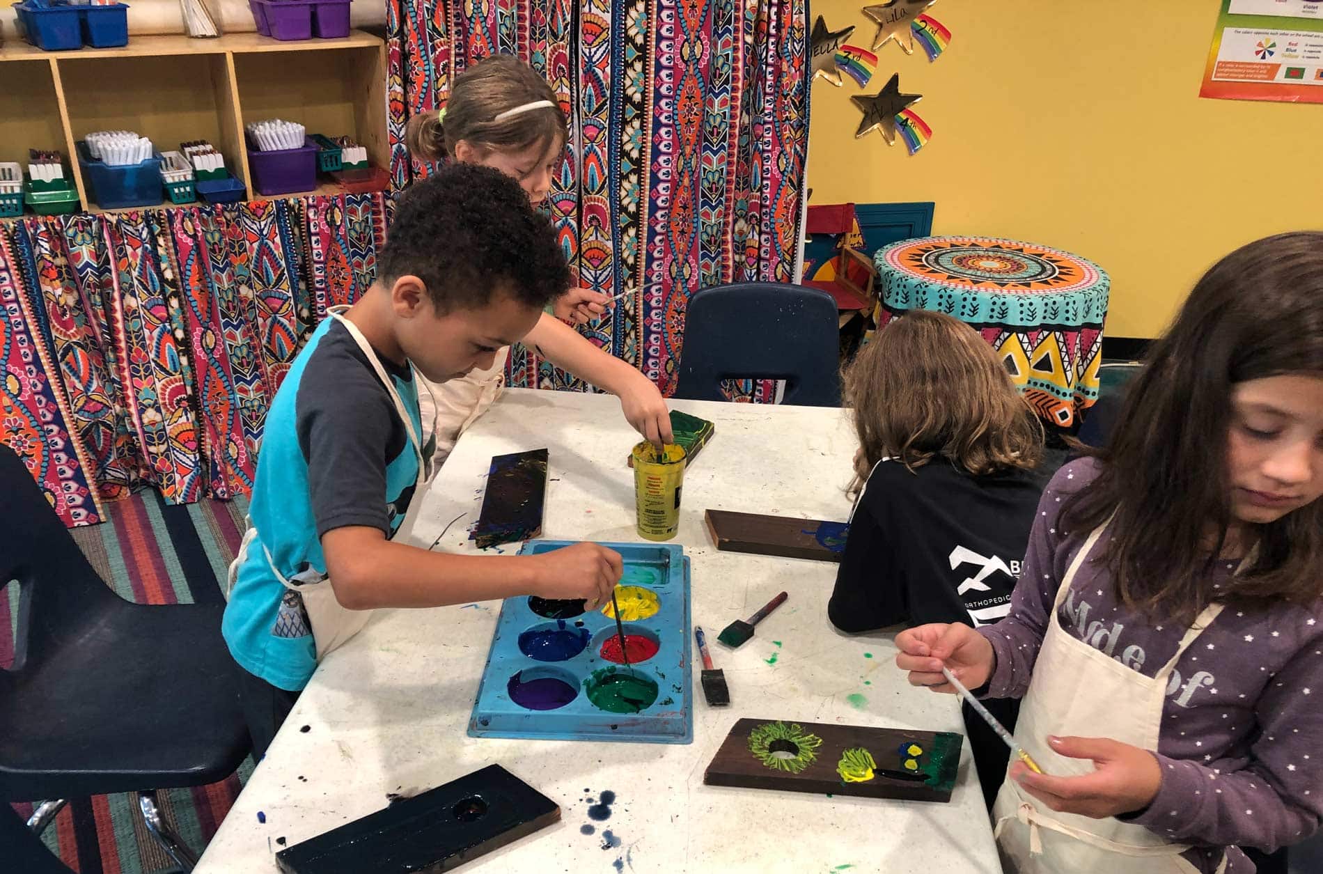 elementary school student painting at classroom table