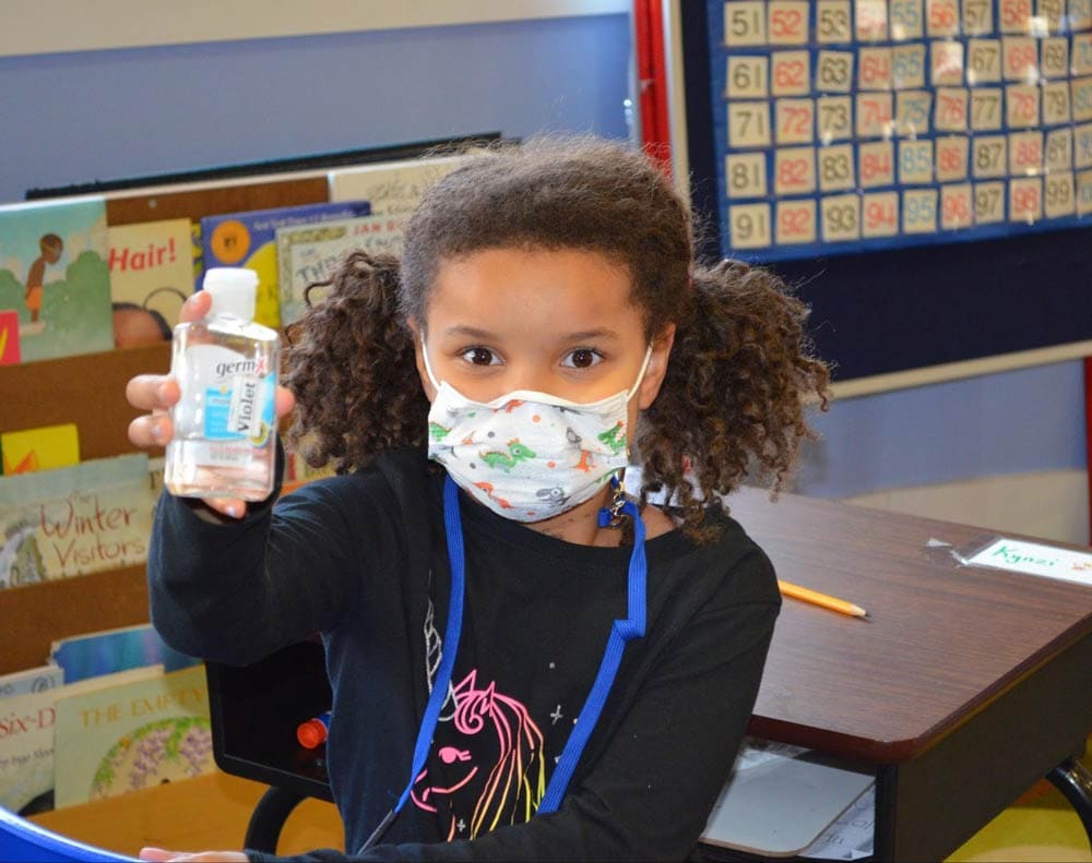 young student holding sanitizer wearing mask